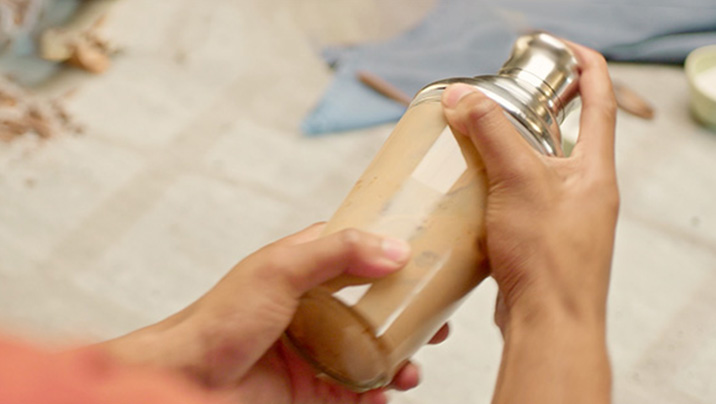 мужчина встряхивает nescafé фраппе капучино с шоколадом в шейкере