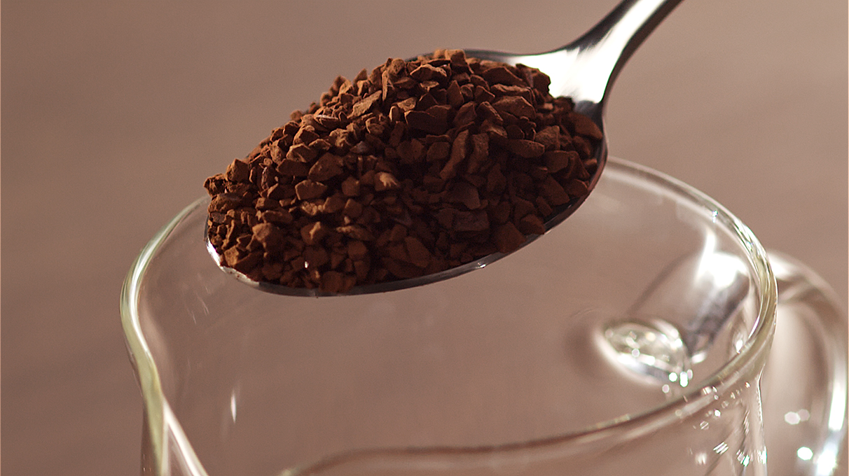 крупным планом кофе высыпается из чайной ложки в прозрачную емкость