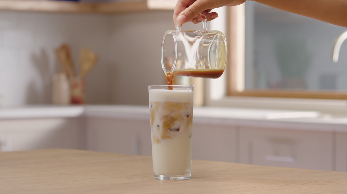 Перелейте молоко и кофе в высокий прозрачный бокал