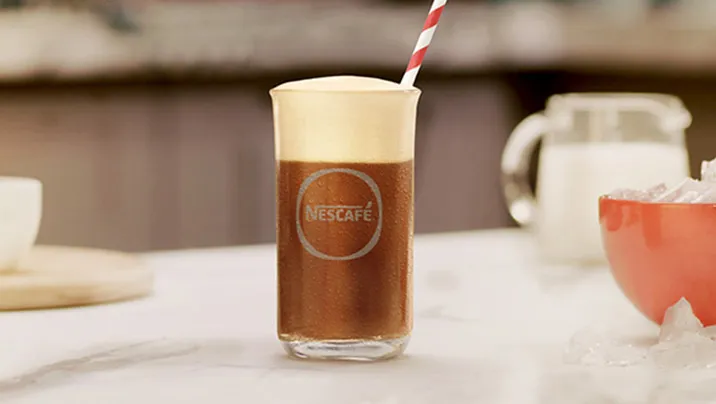 бокал с nescafé фраппе латте на столе